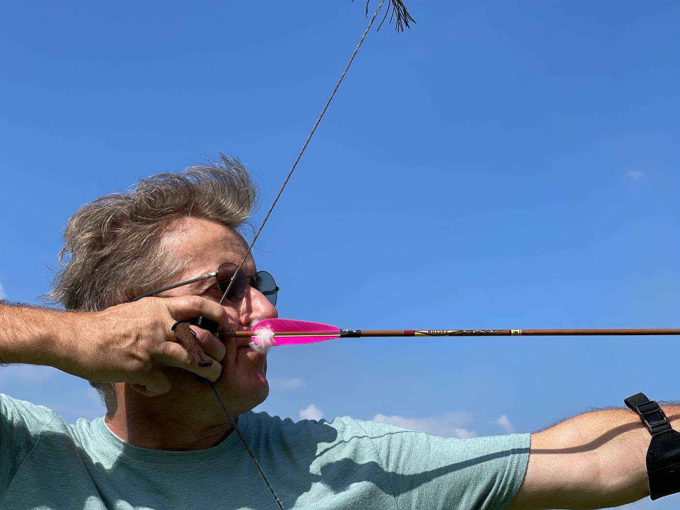 An archer at full draw, anchored, sighting straight down the arrow